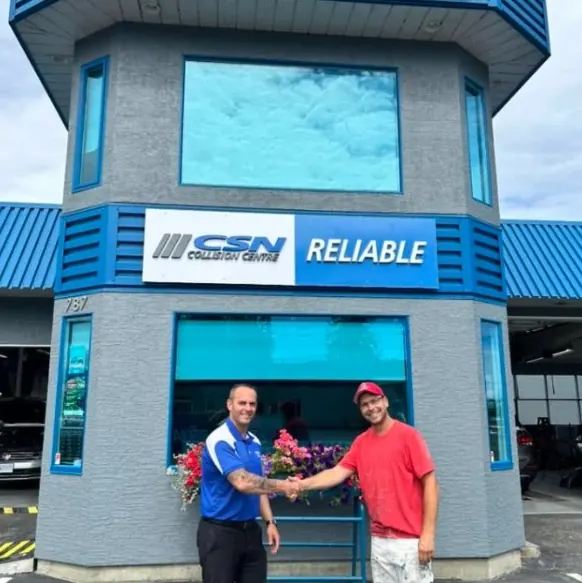 Rory shaking hands with the shop owner in front of the finished building