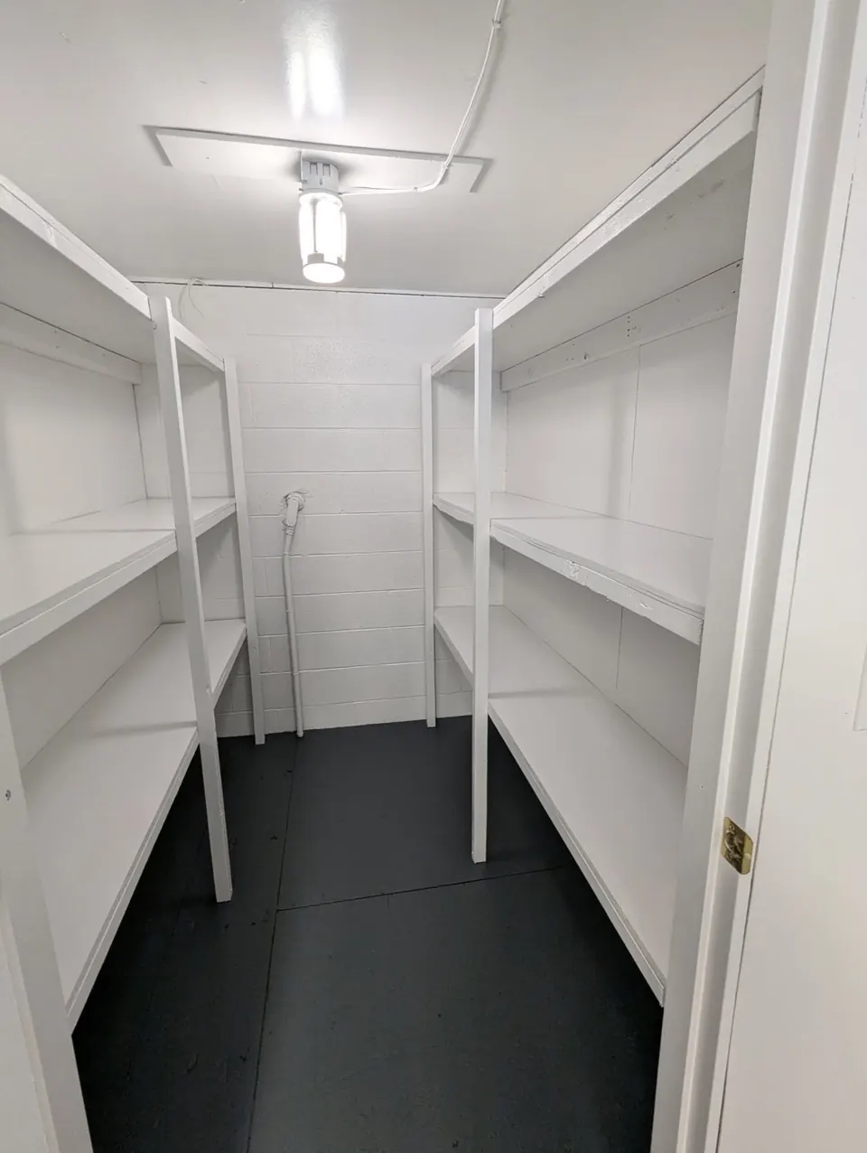 White storage room with shelves and a dark grey floor