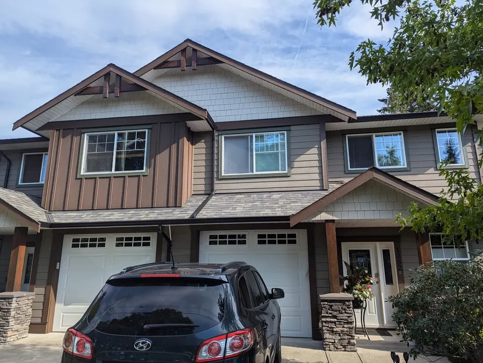 Townhouse with brown and grey siding and white garage doors